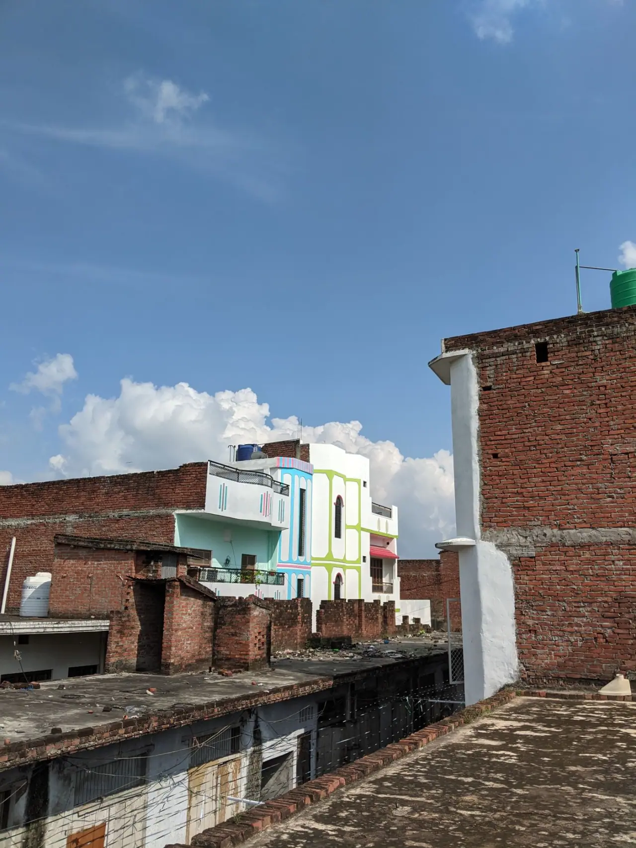 Densely packed painted rooftops and terraces in an Indian town under a clear blue sky